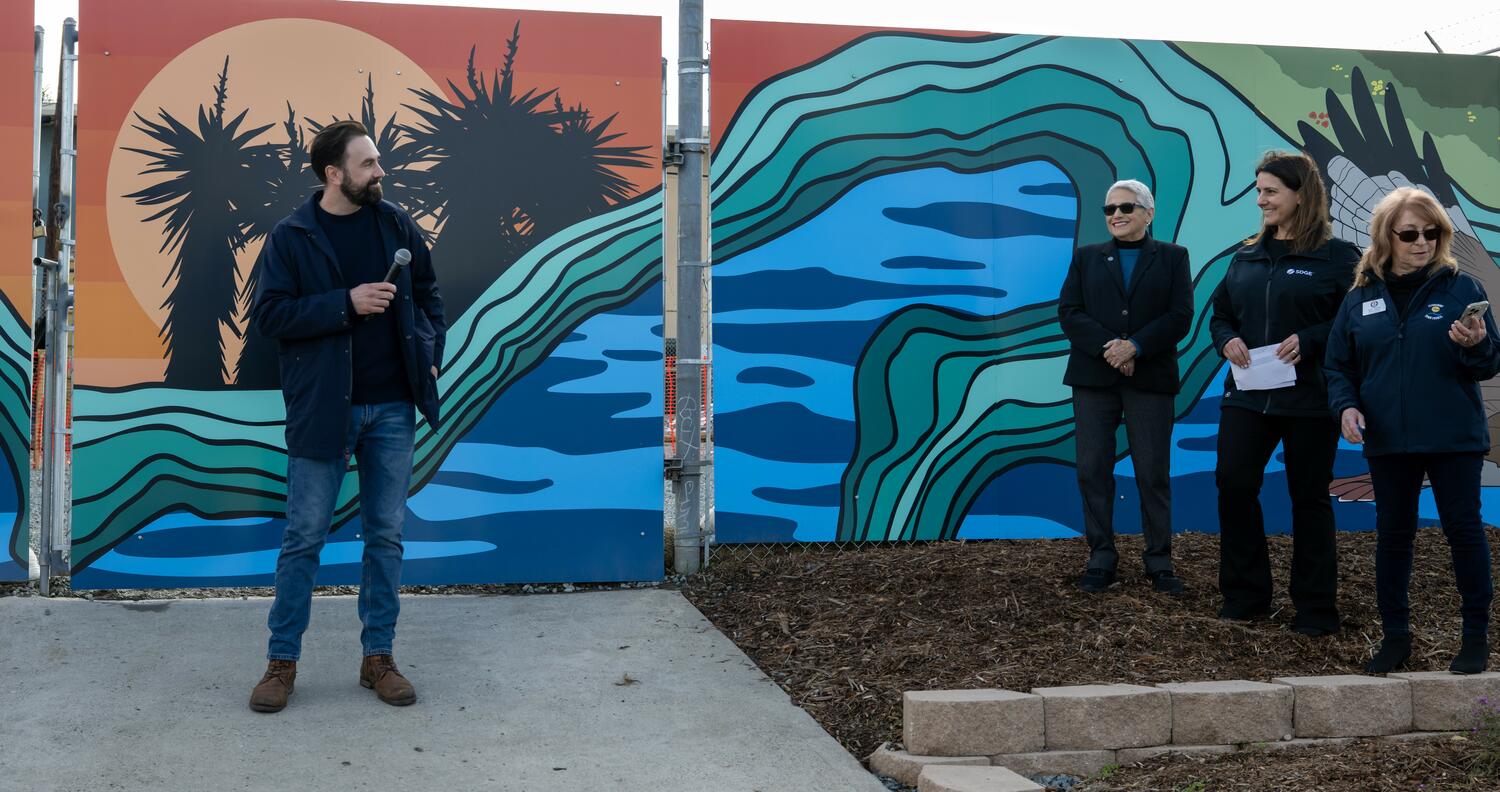 Local artist Stiles-Mikl with the vibrant mural he created behind him.