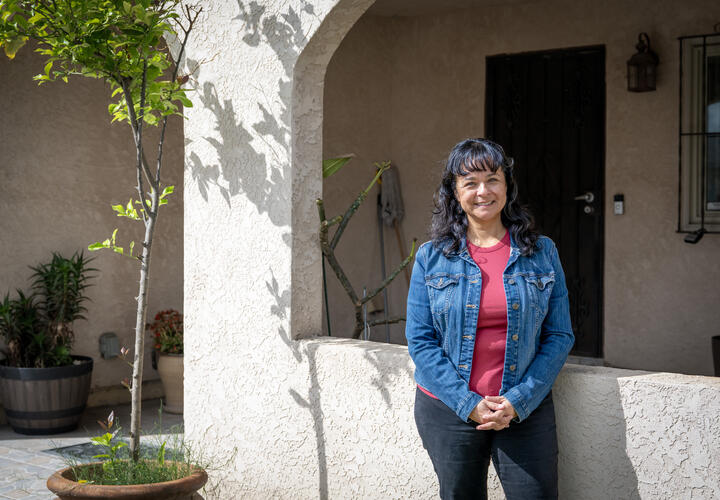 A woman poses in front of her home.