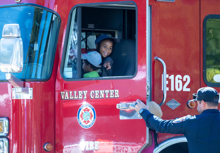 A child seated in a bright red fire truck, smiling