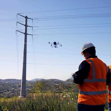 Two SDGE crew members flying a drone near power lines.