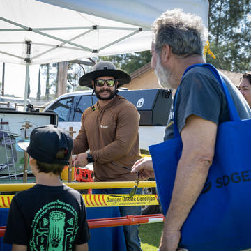 Image of a young child and a middle-aged man observe an energy demonstration at the SDG&E wildfire safety fair.