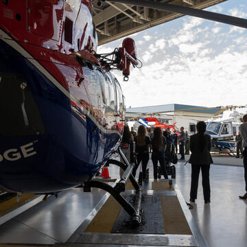 An image that shows the back of a helicopter with an SDG&E logo and a press conference taking place in the background.