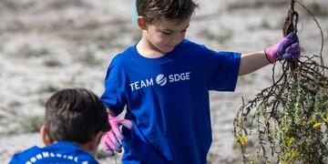 A young boy holding vegetation waste during a volunteer event at mission bay San Diego.