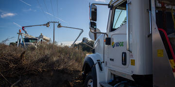 An SDG&E truck in the foreground and field crews operating equipment in the background.