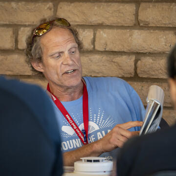 A male American red cross voulnteer demonstrates proper fire alarm installation techniques to new volunteers