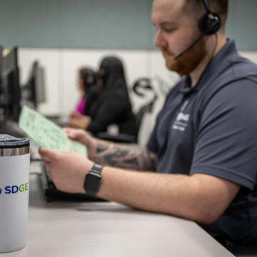 Male customer service representative reviews document at a computer workstation
