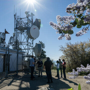 People stand in a gathering around weather-monitoring technology infrastructure.