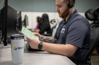 Male customer service representative reviews document at a computer workstation