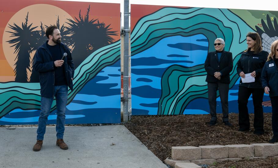 Local artist Stiles-Mikl with the vibrant mural he created behind him.