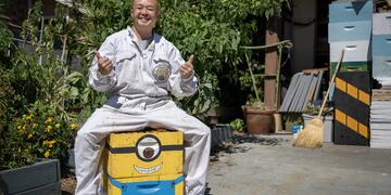 Dan the Bee Man poses for a photo, sitting on a colorful wood box and giving a thumbs up sign. 